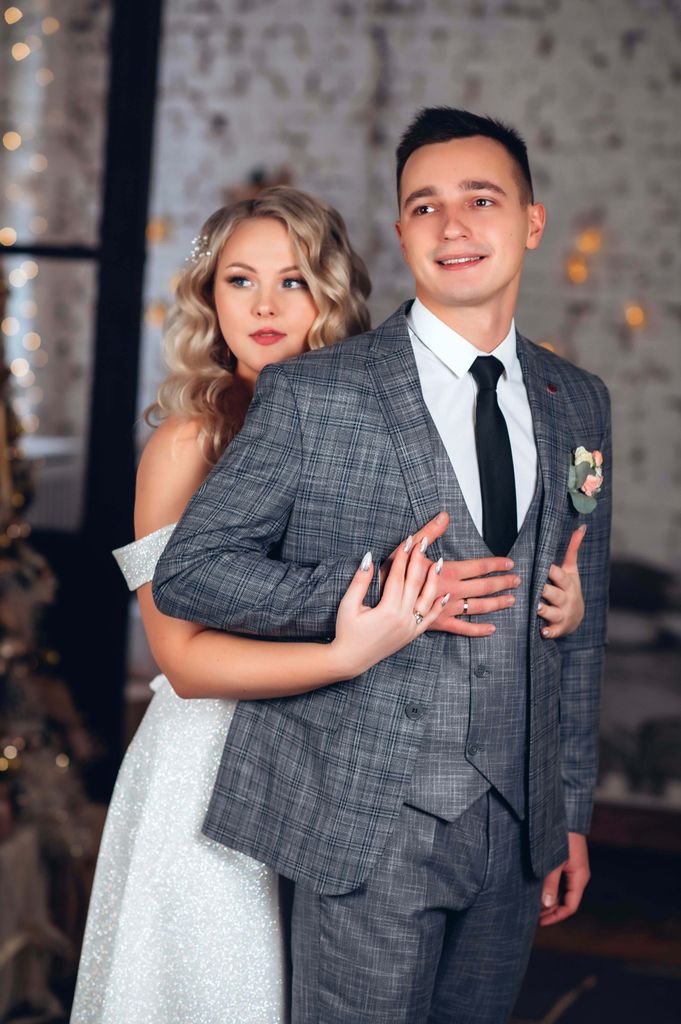 A beautiful bride and groom embracing on their wedding day indoors.