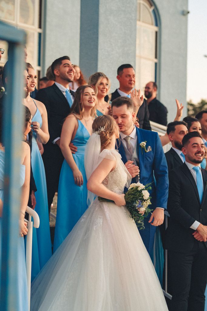 A happy bride and groom with their wedding party in bright blue dresses and suits, celebrating joyfully.